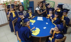 Des enfants en toge de fin d’année autour d’une table